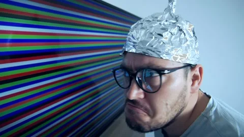 Man wears a tin foil hat expressing fear and disbelief while confronted with Vidéo 307823523