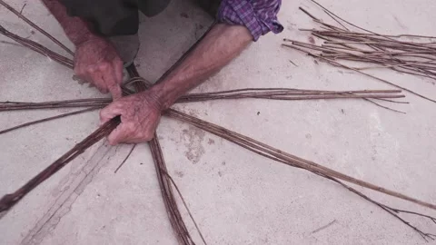 A man is weaving basket using leftover bushes branch and foliage of Stock Footage 237912964