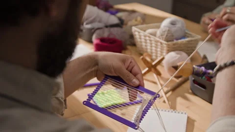 Man Weaving Yarn on Small Plastic Loom at Creative Workshop Stock Footage 341945643