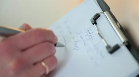 A man with a wedding ring records data on a sheet of paper Stock Footage 61839099