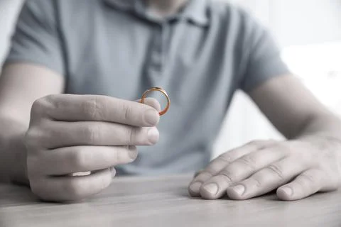 Man with wedding ring at table indoors, closeup. Cheating and breakup Stock Photos