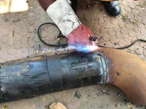 A man is welding a thick iron pipe. Stock Photos