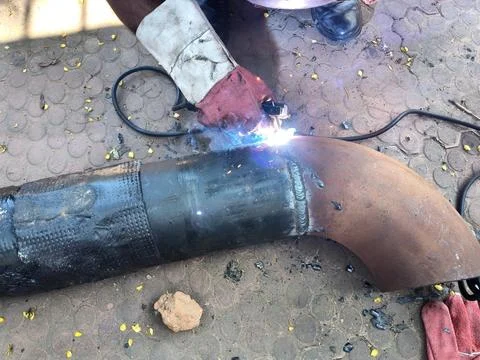 A man is welding a thick iron pipe. Stock Photos