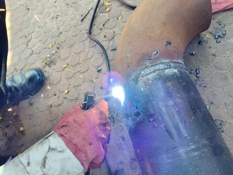 A man is welding a thick iron pipe. Stock Photos