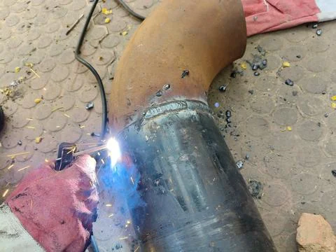 A man is welding a thick iron pipe. Stock Photos