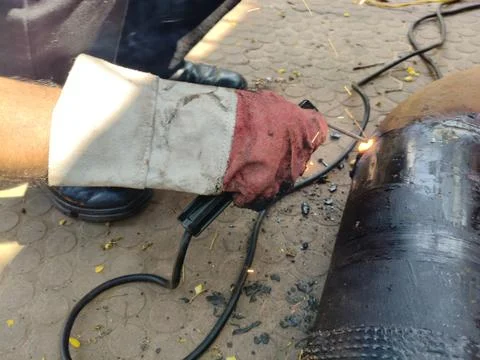 A man is welding a thick iron pipe. Stock Photos