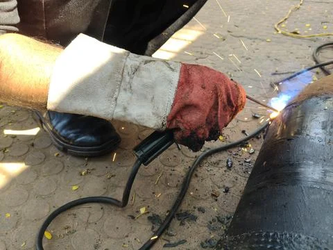 A man is welding a thick iron pipe. Stock Photos