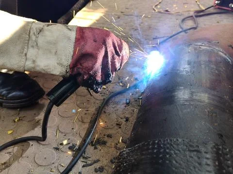A man is welding a thick iron pipe. Stock Photos