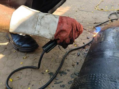A man is welding a thick iron pipe. Stock Photos