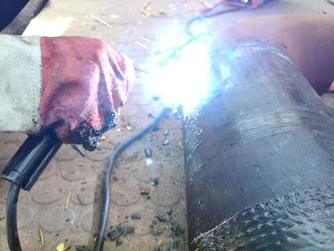 A man is welding a thick iron pipe. Stock Photos