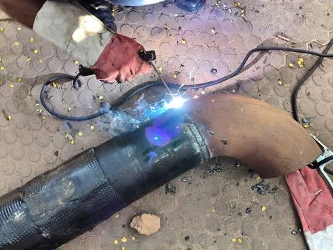 A man is welding a thick iron pipe. Stock Photos