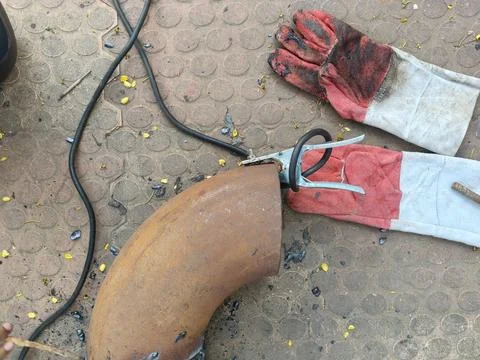 A man is welding a thick iron pipe. Stock Photos