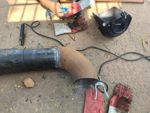 A man is welding a thick iron pipe. Stock Photos