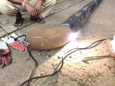 A man is welding a thick iron pipe. Stock Photos