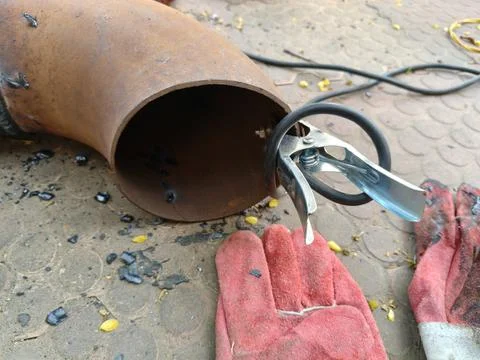 A man is welding a thick iron pipe. Stock Photos