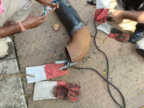 A man is welding a thick iron pipe. Stock Photos