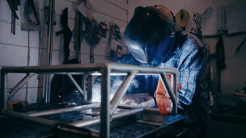 Man welding in workshop wearing welding mask smokey sparks Видео 104077476