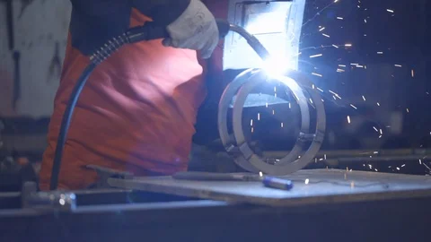 Man welds a circular piece of iron Stock Footage 122084544