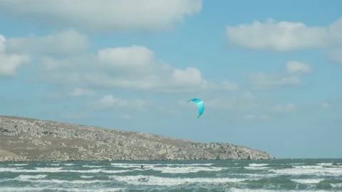 A man in a wetsuit on a parachute rides a board on the waves of the sea. A young Video stock 220416232