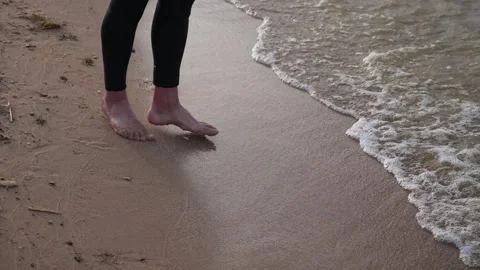 A man in a wetsuit walks on the beach. Bare feet in close-up. Stock Footage 274062469