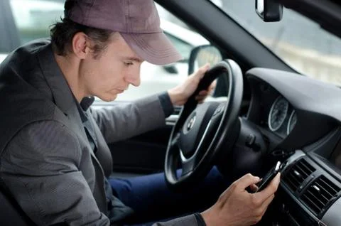 Man at wheel using cell mobile phone while driving car Stock Photos