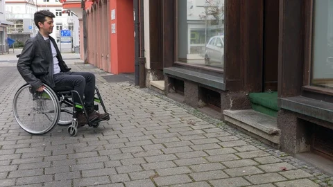 A man in a wheelchair cannot drive into a small shop Stock Footage 125537064
