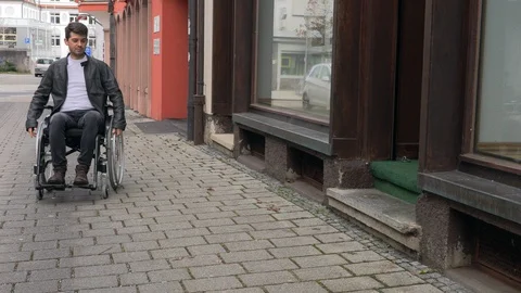 A man in a wheelchair cannot drive into a small shop Stock Footage 125537191