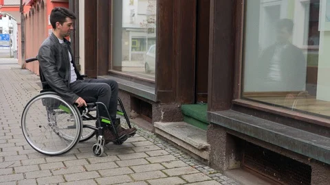 A man in a wheelchair cannot drive into a small shop Stock Footage 125537544