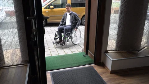 A man in a wheelchair cannot drive into a small shop Stock Footage 125538182