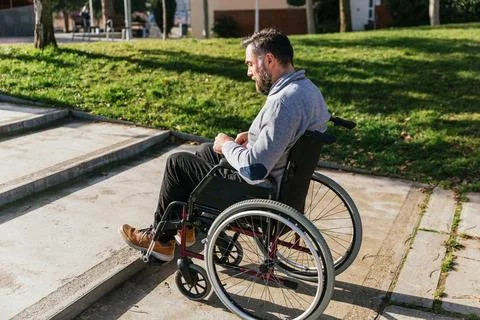 Man in a wheelchair facing accessibility problem in front of the stairs of the Stock Photos
