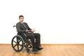 The man in the wheelchair gesturing on the white wall background Photo