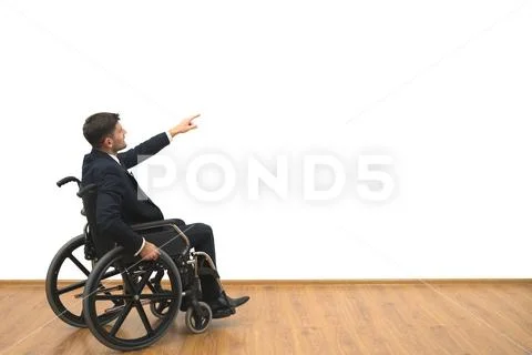 The man in a wheelchair gesturing on the white wall background Stock Photos
