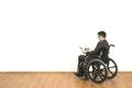 The man in a wheelchair holding papers on the white wall background Photo