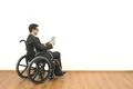 The man in the wheelchair holding a tablet on the white wall background Photo