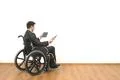 The man in a wheelchair holding a tablet on the white wall background Photo