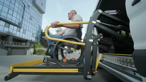A man in a wheelchair on a lift of a vehicle for people with disabilities.  Stock Footage 142277186