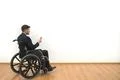 The man in a wheelchair phones on the white wall background Photo