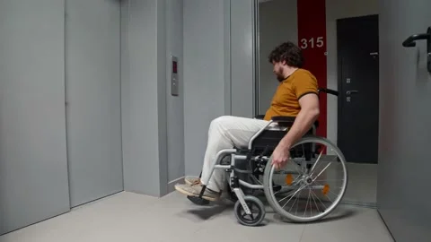 Man in a wheelchair rolling to an elevator and press the button Video stock 178098398