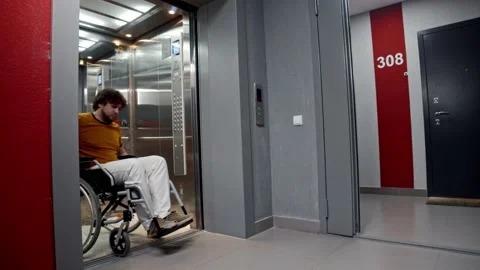 Man in a wheelchair rolling out of an elevator Stock Footage 178098125