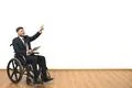 The man in a wheelchair with a tablet gesturing on the white wall background Photo