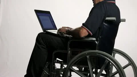 MAN IN WHEELCHAIR TYPING ON LAPTOP COMPUTER Stock Footage 10727631