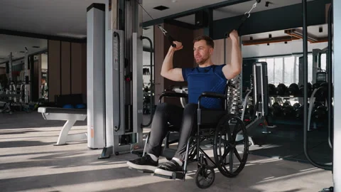 Man in wheelchair using lat pulldown machine in gym Video stock 309068154