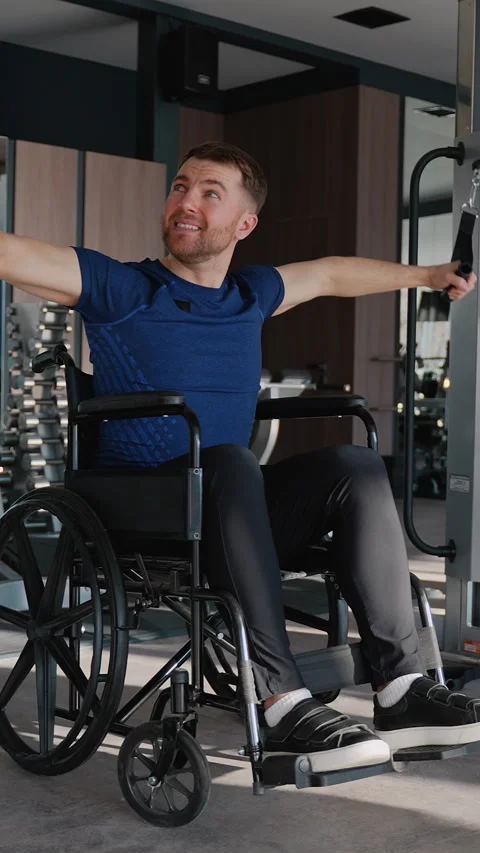 Man in wheelchair using lat pulldown machine in gym Stock Footage 309070044