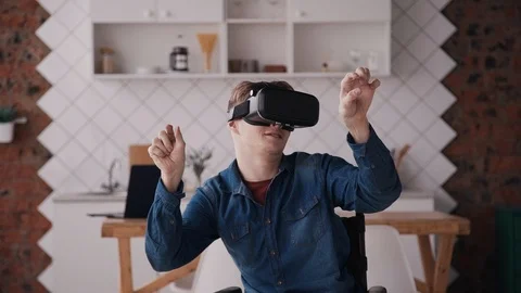 Man in wheelchair using virtual reality helmet or glasses at hom Stock Footage 112428445