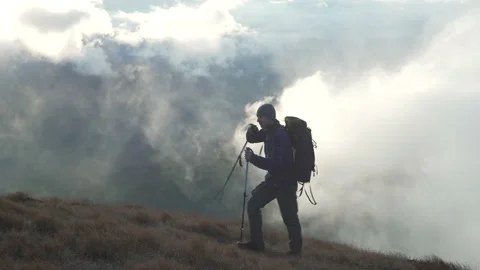 A man while hiking in the mountains shrouded in clouds. A man walks above sky Stock Footage 213016918