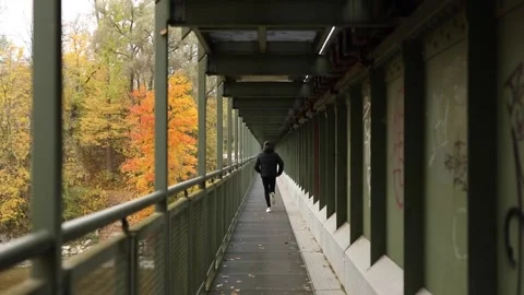 Man while running on a metal construction during fall season Stock Footage 171083235