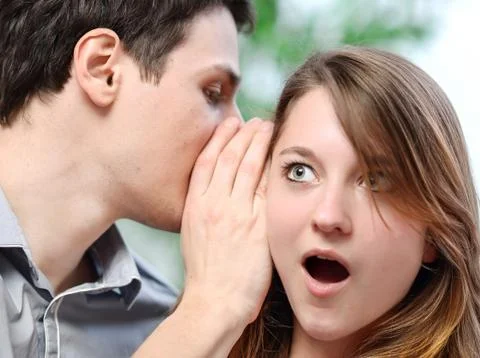 Man whispering in the ear of his surprised wife Stock Photos