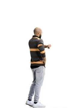 A man, on a white background, in full height, looks at his watch Stock Photos