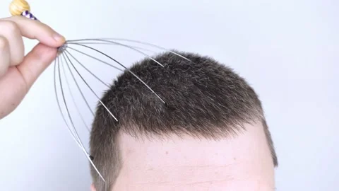A man on a white background makes himself a head massage with a capillary massag Stock Footage 147191123
