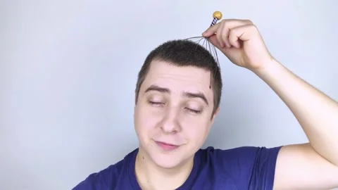 A man on a white background makes himself a head massage with a capillary massag Stock Footage 147191151